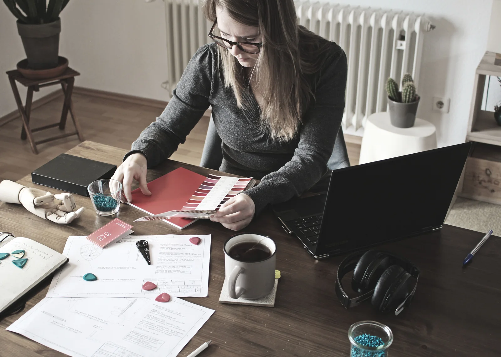 Persona trabajando con un portátil, papeles y una carta de colores sobre el escritorio.