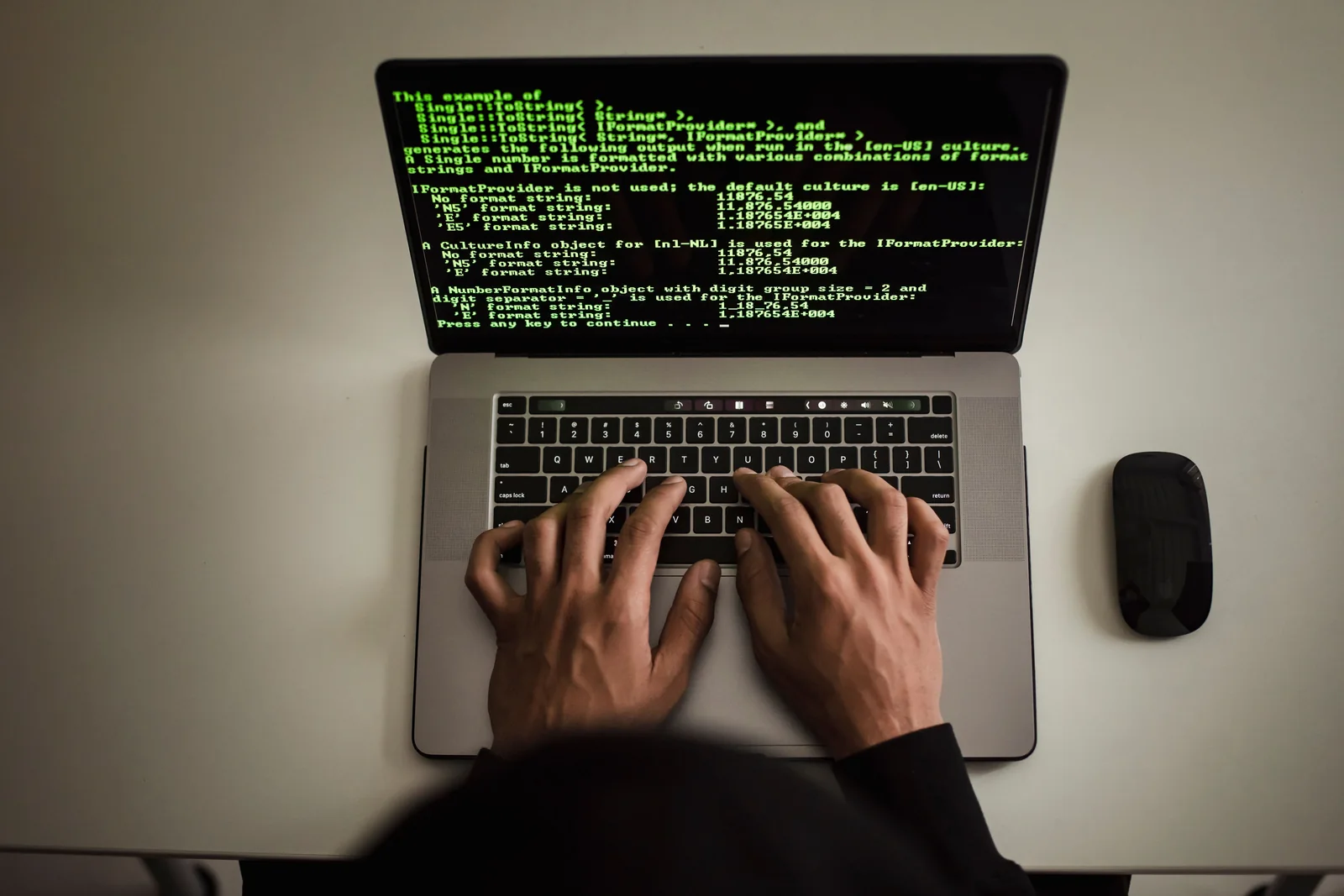Manos utilizando un portátil con código de programación en pantalla.