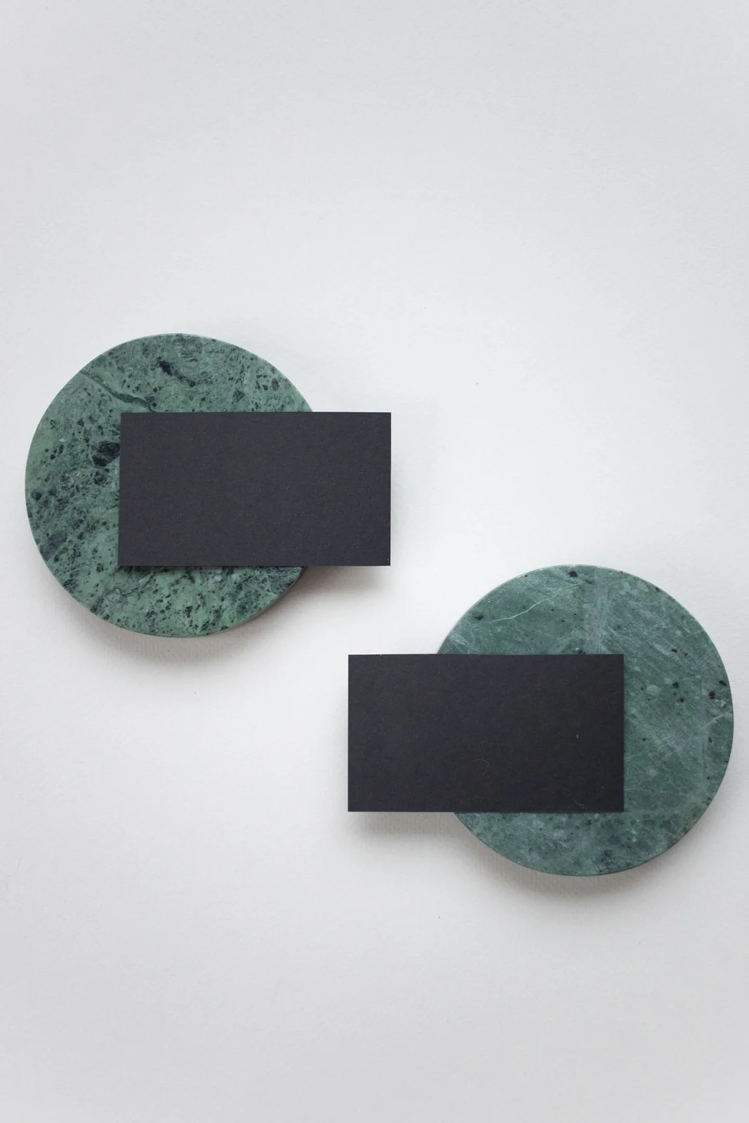 Tarjetas de papel negras sin impresión sobre soportes verdes y una mesa clara.