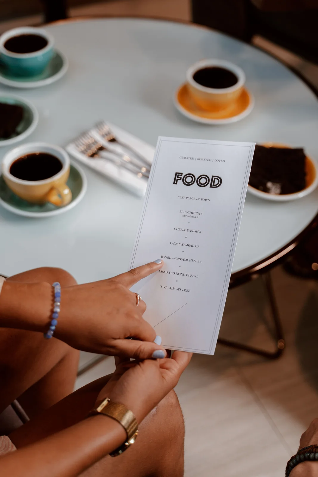 Primer plano de manos consultando una carta de restaurante sobre una mesa.